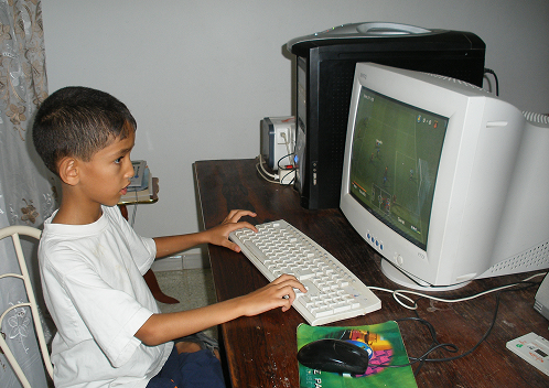A boy playing a game on an early desktop computer