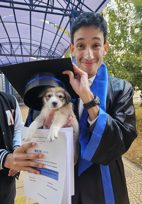 A graduate in cap and gown holding a puppy